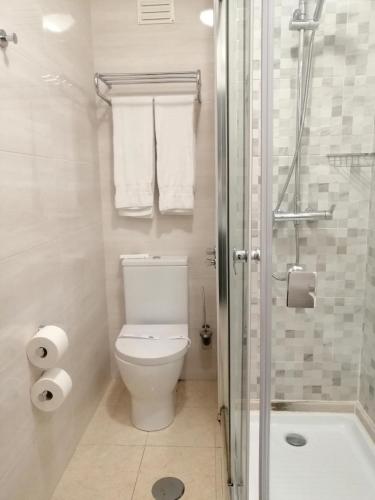 a bathroom with a toilet and a shower with towels at Vera Cruz Porto Downtown Hotel in Porto