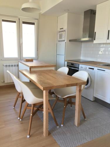 a kitchen with a wooden table and white chairs at La Casita del Alcázar in Medina de Pomar
