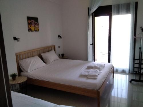 a bedroom with a bed with white sheets and a window at Ioannas in Nikiti