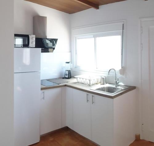 una cucina con armadi bianchi, lavandino e finestra di Loft Con Encanto a Frontera