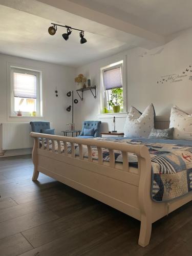 a bedroom with a large bed with two blue chairs at Ferienwohnungen Lausbuben & Zicken - im grünen Herzen Deutschlands in Herleshausen