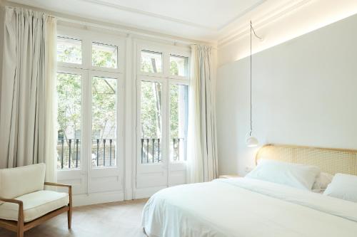 a white bedroom with a bed and a chair at The MO House in Barcelona