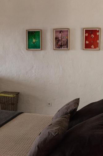 a bedroom with a bed with three pictures on the wall at Casas do Amarelo in São Mateus