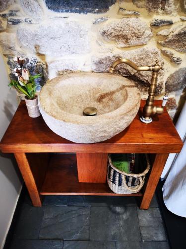 a stone sink on a wooden table with flowers at El Cuarto in Suarbol