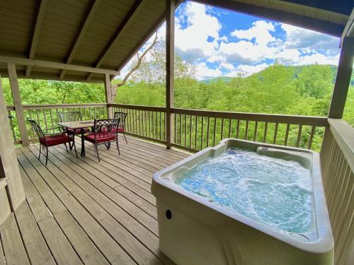 a hot tub on a deck with a table and chairs at Secluded Riverview with River Access in Townsend