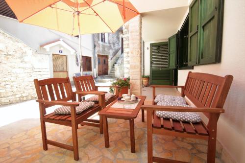 a patio with two chairs and a table with an umbrella at Holiday house Ljubica Tisno in Tisno