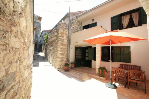 an orange umbrella sitting outside of a house at Holiday house Ljubica Tisno in Tisno