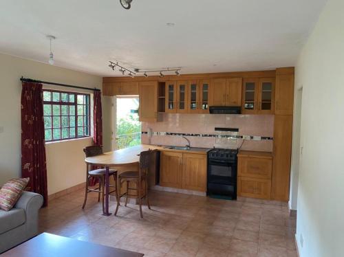 a kitchen with wooden cabinets and a table and chairs at Twiga Hill Gardens in Nairobi