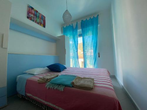 Schlafzimmer mit einem Bett mit blauen Vorhängen und einem Fenster in der Unterkunft Raggi di Sole in Monterosso al Mare