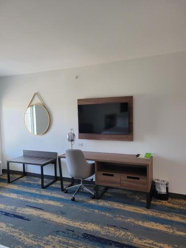 a living room with a table and a chair and a television at La Quinta Inn & Suites by Wyndham Terrell in Terrell