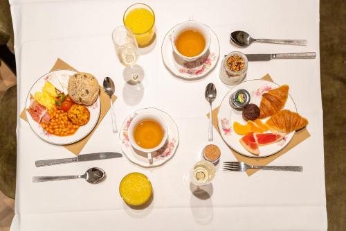 a white table with plates of food and cups of coffee at Grand Hotel Normandy by CW Hotel Collection in Bruges