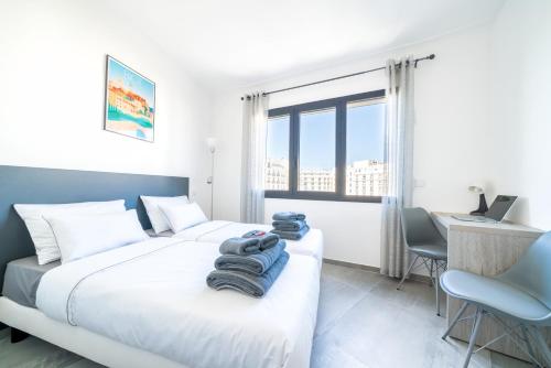 1 dormitorio con 2 camas, escritorio y ventana en La Rotonde YourHostHelper, en Cannes