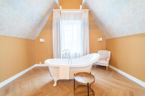 a white bath tub in a room with a window at Grand Hotel Normandy by CW Hotel Collection in Bruges