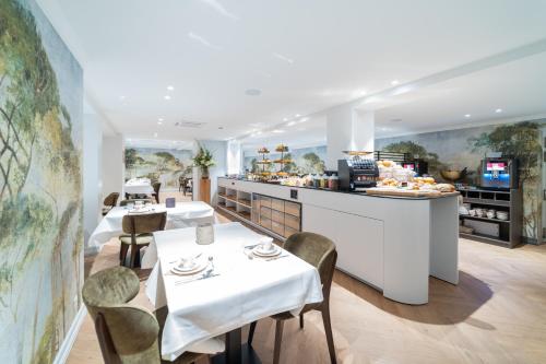 a restaurant with white tables and chairs and a counter at Grand Hotel Normandy by CW Hotel Collection in Bruges