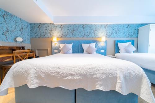 a bedroom with a large white bed with blue wallpaper at Grand Hotel Normandy by CW Hotel Collection in Bruges