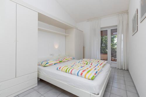 biała sypialnia z łóżkiem i oknem w obiekcie Apartament Kormorano w mieście Malcesine