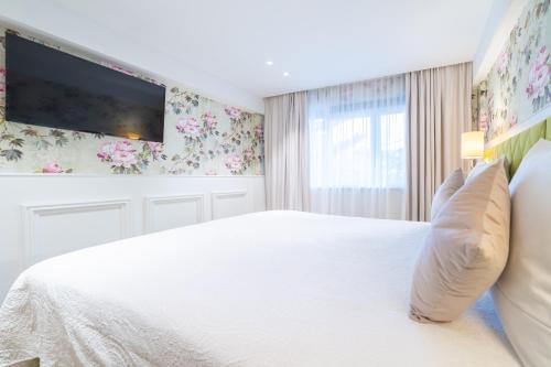 a bedroom with a white bed with a tv on the wall at Grand Hotel Normandy by CW Hotel Collection in Bruges