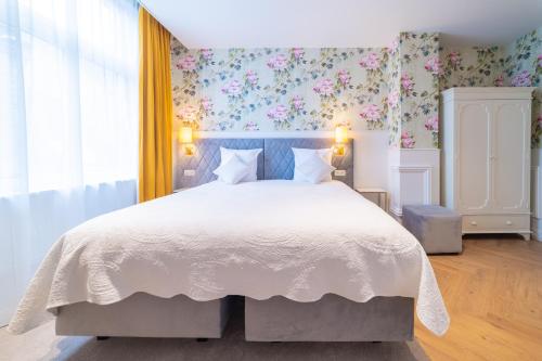 a bedroom with a large white bed with floral wallpaper at Grand Hotel Normandy by CW Hotel Collection in Bruges