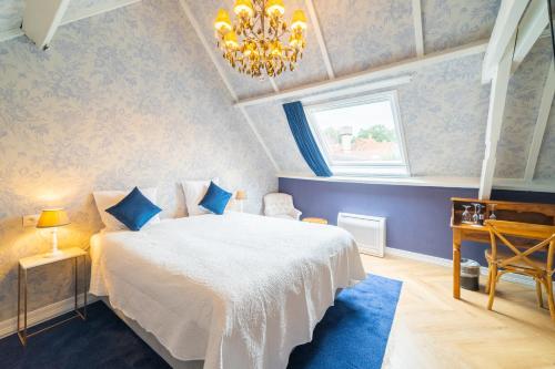 a bedroom with a white bed and a chandelier at Grand Hotel Normandy by CW Hotel Collection in Bruges
