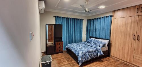 1 dormitorio con cama y cortina azul en Mama Jane's Villa en Akim Oda