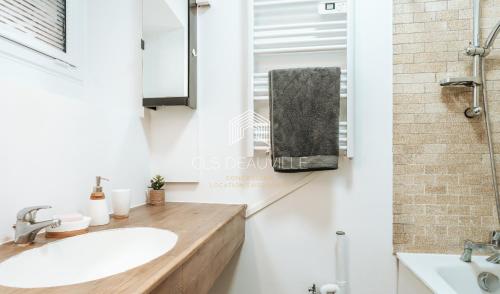 a bathroom with a sink and a mirror at Le Ponton C.L.S Deauville in Deauville