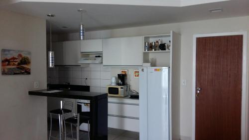 a kitchen with white cabinets and a white refrigerator at FLAT frente Mar Green Diamond in Vila Velha