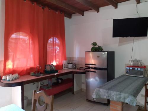 eine Küche mit einem Kühlschrank aus Edelstahl und einem Tisch in der Unterkunft Cabinas coco azul Guanacaste in Guanacaste