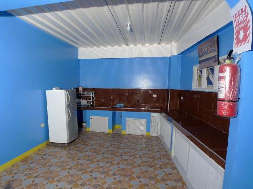 a kitchen with blue walls and a white refrigerator at RAVARA NATIVIDAD PENSION HOUSE in Alaminos