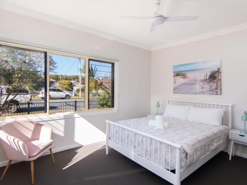 a white bedroom with a bed and a window at 9 Breckenridge Street in Forster