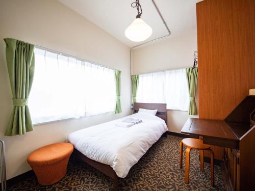 a bedroom with a bed and a desk and a piano at tune HIGORO in Tateyama