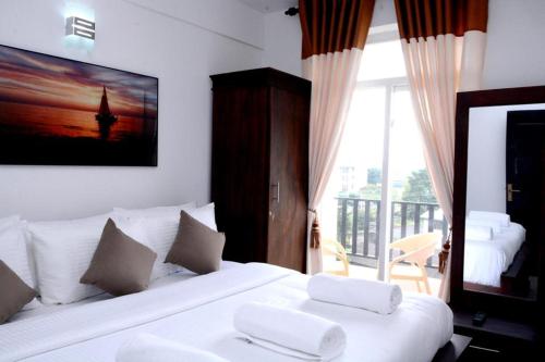 a hotel room with two white beds and a balcony at The Grand Royal Luxury Apartment in Nuwara Eliya