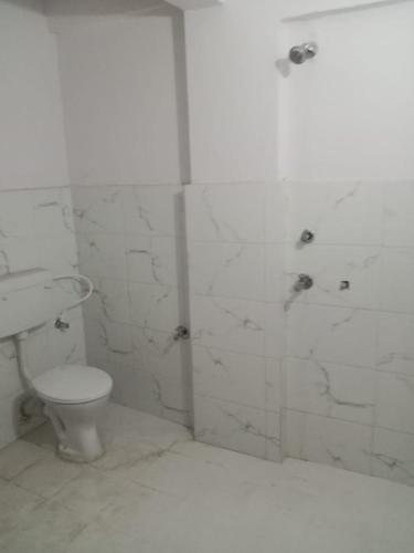 y baño blanco con aseo y ducha. en Hotel New Eastern, en Bokāro