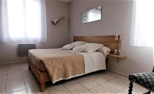 - une chambre avec un grand lit et une tête de lit en bois dans l'établissement Gîte le Micocoulier, à Valréas
