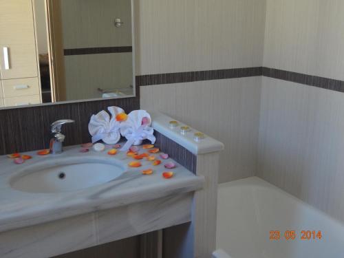 een badkamer met een wastafel met pillen en bloemen erop bij Aegea Hotel in Karistos