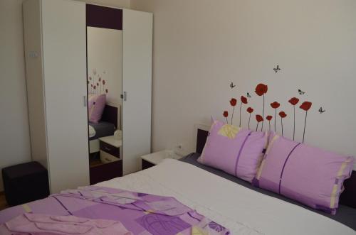 Apartments Mare في باشكا: غرفة نوم بها سرير ووسائد أرجوانية ومرآة
