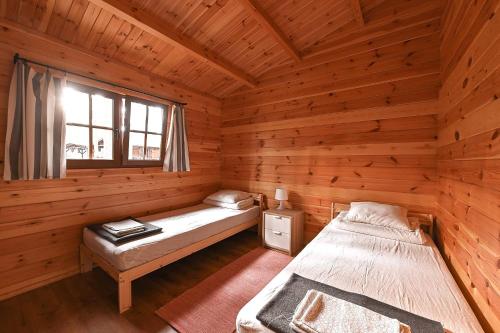 a bedroom with two beds in a wooden cabin at Leśniczówka-Wdzydze Pe eL in Wdzydze Kiszewskie