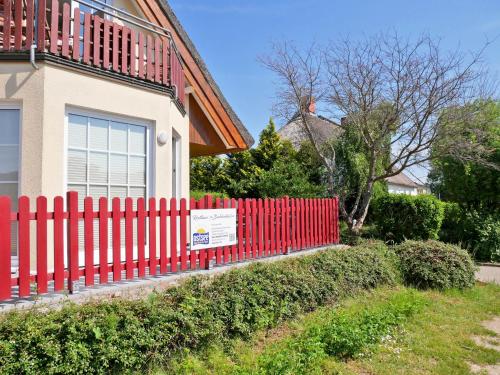 ein roter Zaun vor einem Haus in der Unterkunft Reethaus Boddenblick - Apt. 09 in Alt Reddevitz