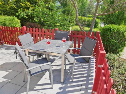 a table with three chairs and two glasses of wine at Reethaus Boddenblick - Apt. 09 in Alt Reddevitz