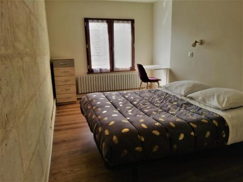 a bedroom with a bed with a chair and a window at Maison Bel Être Langeais in Langeais