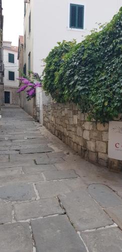 an alley with a stone wall and purple flowers at Antea in Split