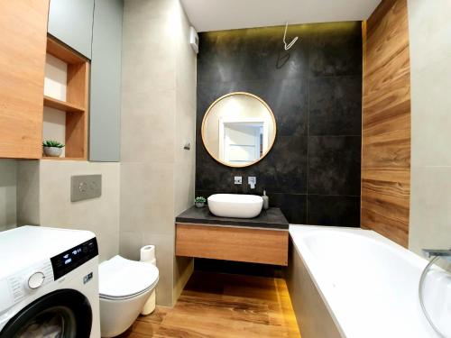 a bathroom with a sink and a washing machine at Apartament 40 in Iława