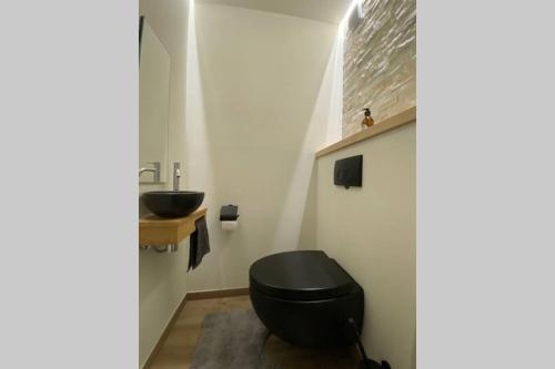 a bathroom with a black toilet and a sink at Ozzy ‘s Place in Ostend