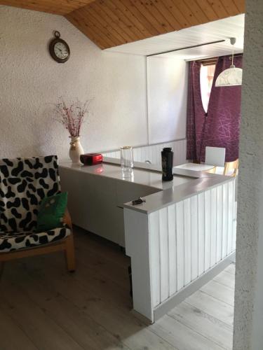 a kitchen with a counter and a chair and a clock at APPARTEMENT DE MONTAGNE in Mijoux