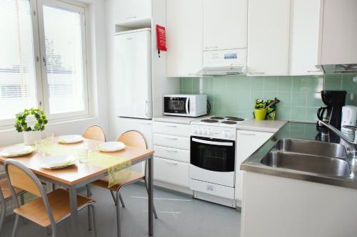 a kitchen with white cabinets and a table and a sink at ISLO Hostel in Joensuu