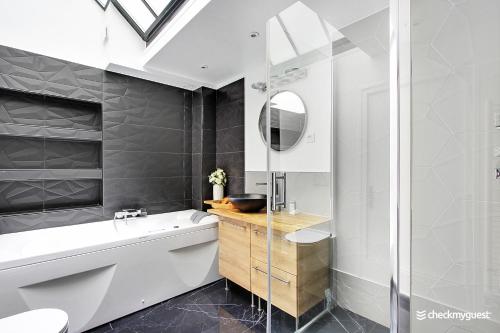 uma casa de banho com uma banheira, um lavatório e um espelho. em CMG Faubourg Saint-Martin em Paris