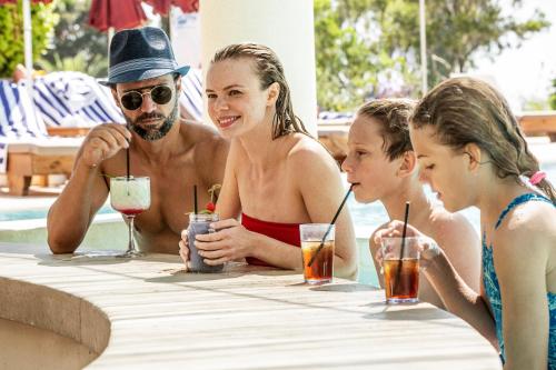 a man and two children sitting at a table with drinks at St Raphael Resort in Limassol
