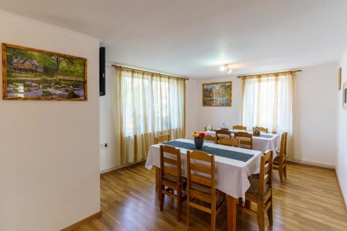 uma sala de jantar com mesas, cadeiras e janelas em Casa Primaverii em Rasnov