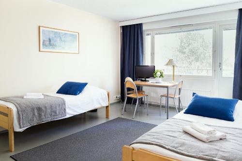 um quarto de hotel com duas camas e uma secretária em ISLO Hostel em Joensuu