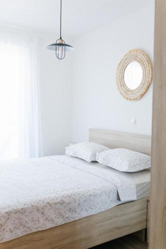 Schlafzimmer mit einem Bett mit weißer Bettwäsche und einem Spiegel in der Unterkunft Apartmani Toma in Pakoštane