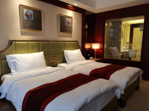 a hotel room with two beds and a mirror at Dynasty International Hotel Dalian in Jinzhou